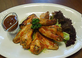 Hostinec Staré Časy - Ostrov u Macochy - Spicy chicken wings served on lettuce leaves with BBQ sauce.